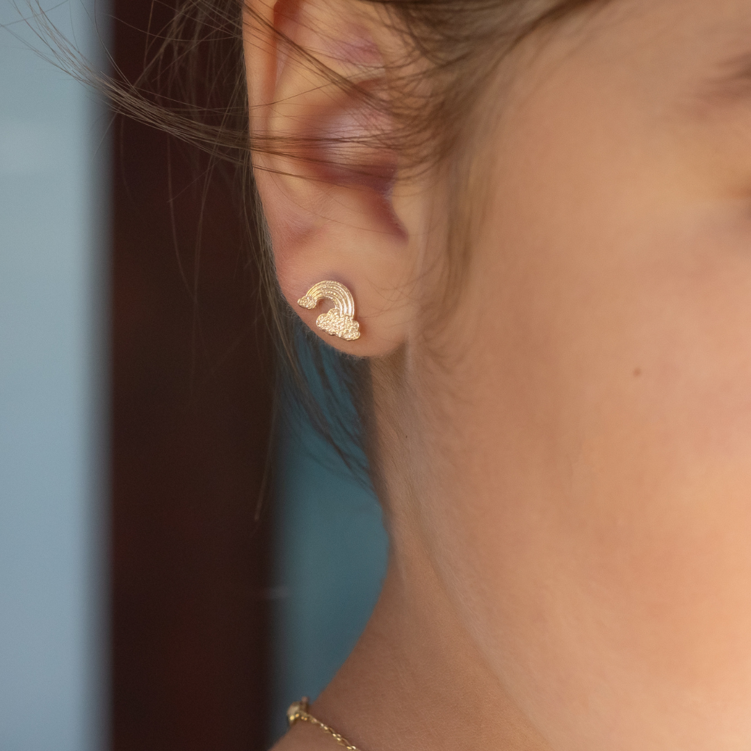 Close-up of a person wearing gold earrings with a blurred background