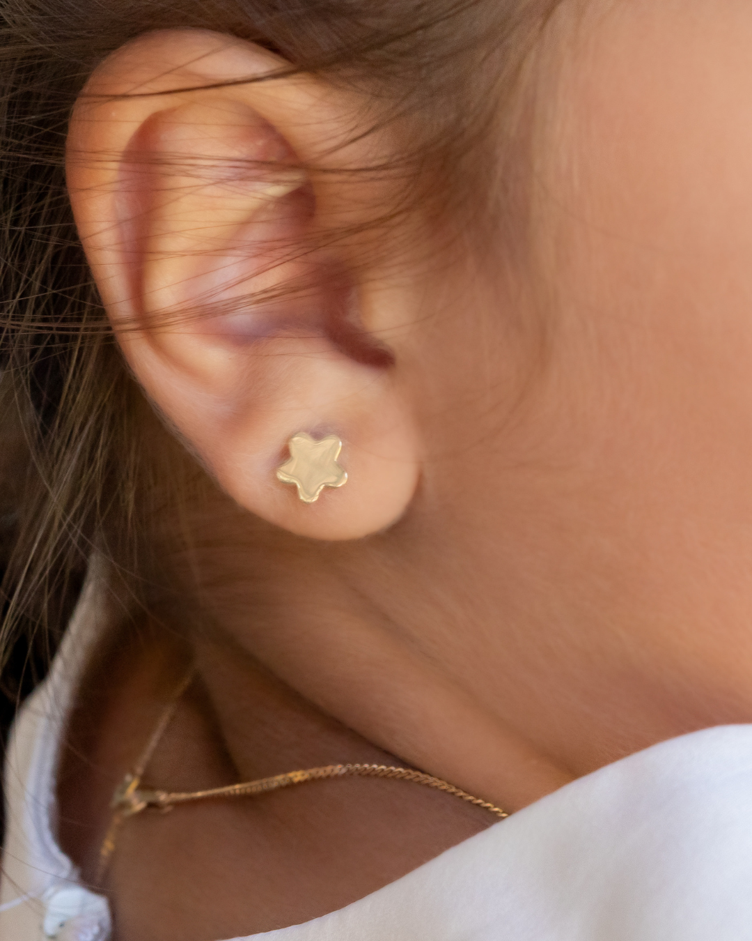 Close-up of a person wearing a gold star-shaped earring.