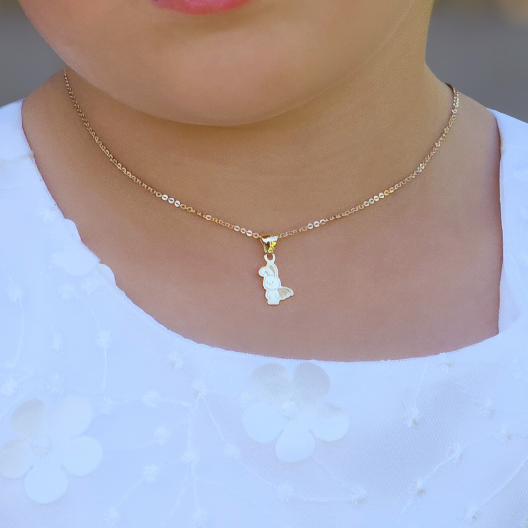 Gold necklace with a small pendant worn by a person against a white background