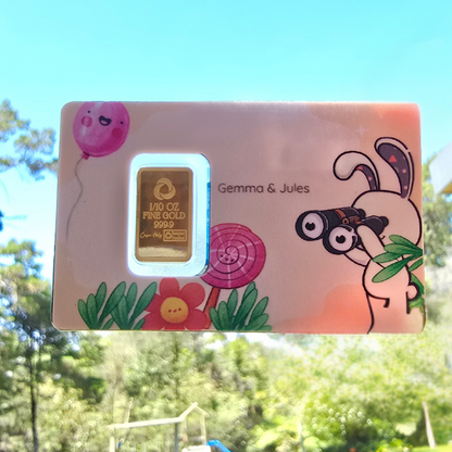 Gold bar in a colorful box with cartoon characters and 'Gemma & Jules' branding, outdoors.