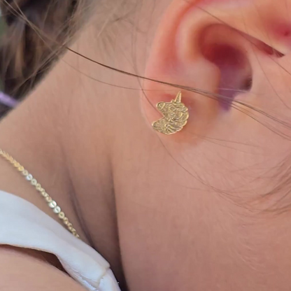 Gold unicorn earring worn by a person
